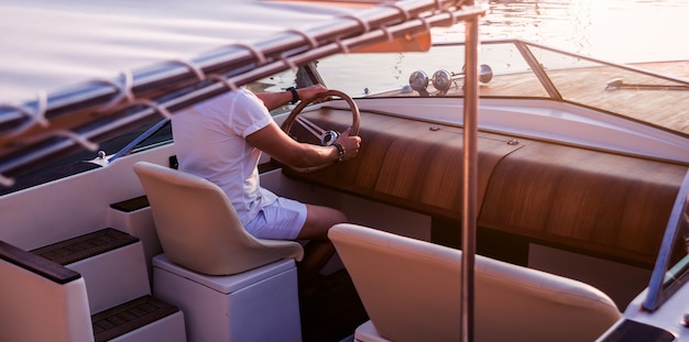 Jovem em iate à vela. as mãos seguram o volante