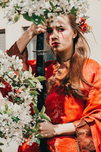 Jovem em kimano tradicional em um jardim florido com katana de espada japonesa samurai na imagem de uma mulher guerreira