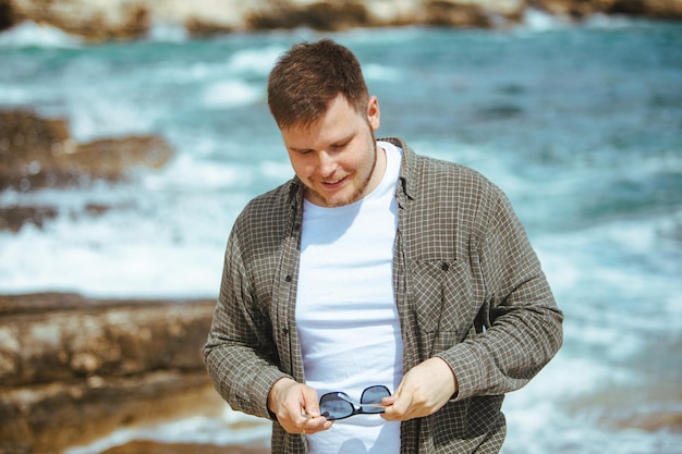 Jovem em óculos de sol com retrato de barba nas férias de verão à beira-mar