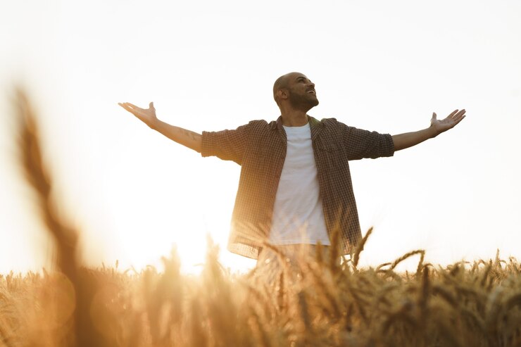 Foto jovem em pé no campo de trigo ao pôr do sol