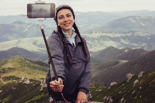 Jovem em pé no topo de um penhasco tirando uma selfie