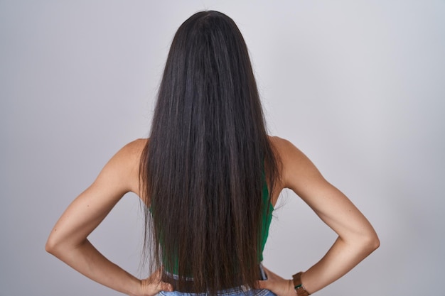 Jovem em pé sobre um fundo isolado, em pé para trás, olhando para longe com os braços no corpo