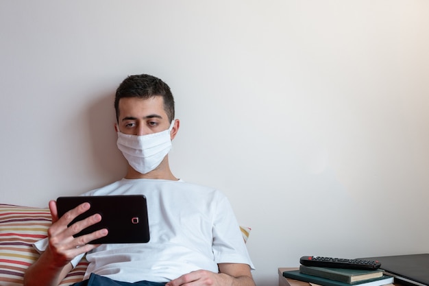 Foto jovem em quarentena assistindo a vídeos em um tablet