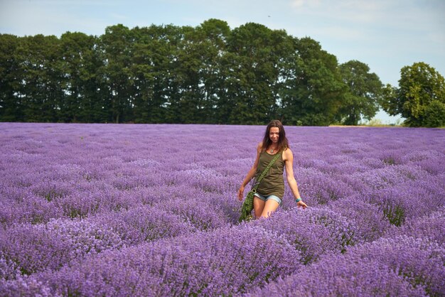 Jovem em roupas casuais caminha por um campo de lavanda florescendo