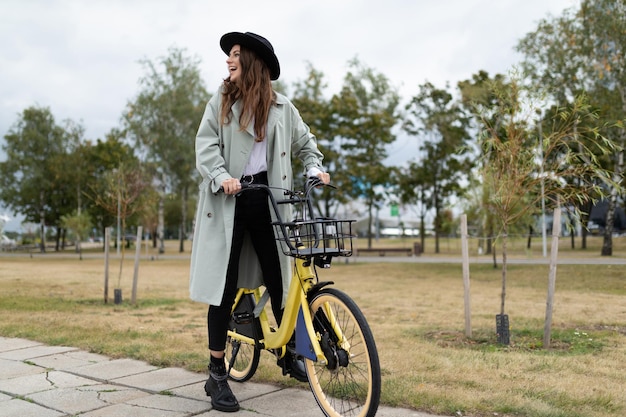 Jovem em roupas elegantes de outono anda de bicicleta no conceito de estilo de vida saudável do parque da cidade