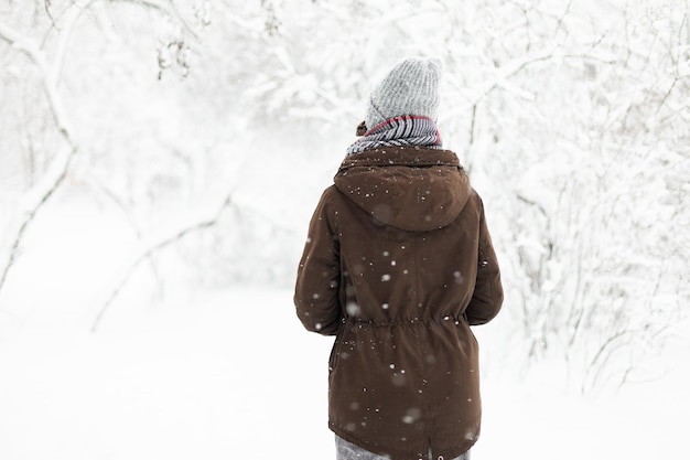 Jovem em roupas quentes em clima de inverno nevado ao ar livre vista traseira