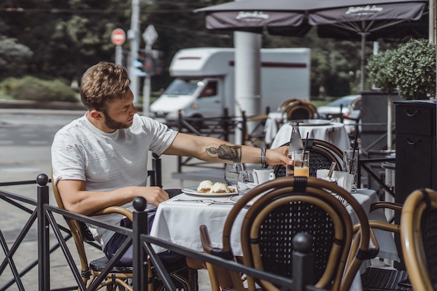 jovem em um café de verão no terraço toma café da manhã