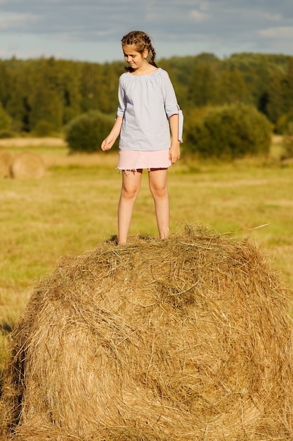 Jovem em um campo de verão. em um rolo de feno.