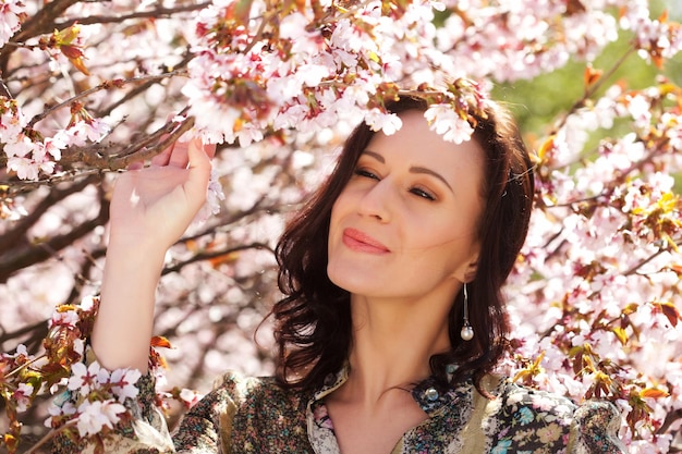 Jovem em um fundo de flores de cerejeira rosa no conceito de estilo de vida de primavera