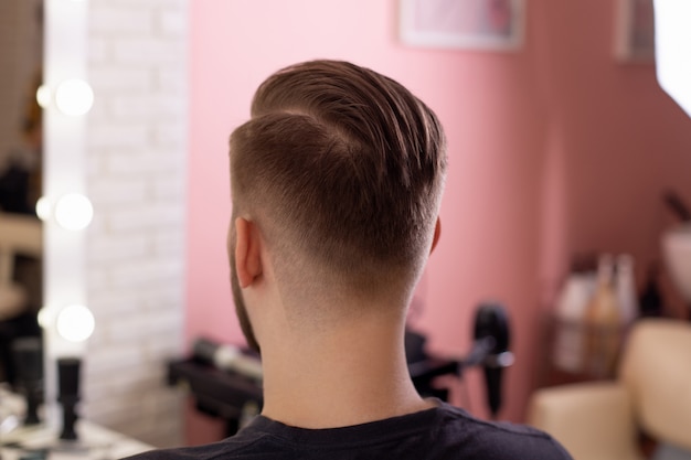 Homem moreno com corte de cabelo elegante no fundo da barbearia