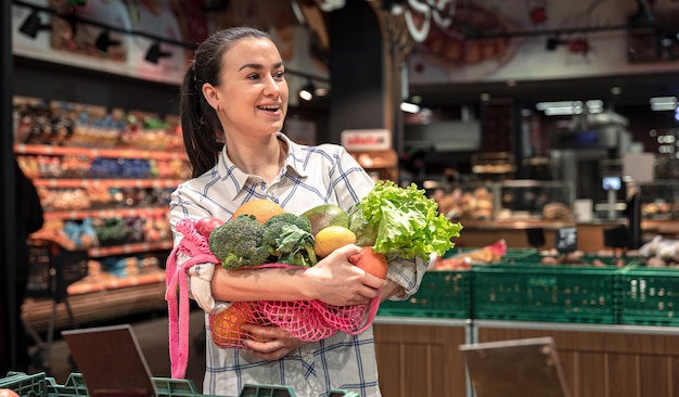 Jovem em um supermercado com legumes e frutas comprando mantimentos