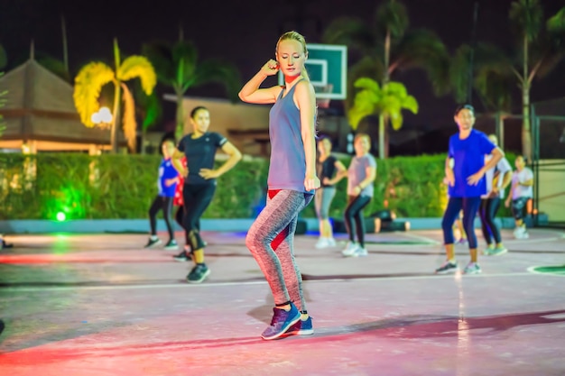 Jovem em um treino em grupo na quadra de basquete à noite