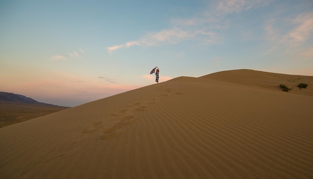 Jovem em um vestido de verão andando nas dunas do deserto