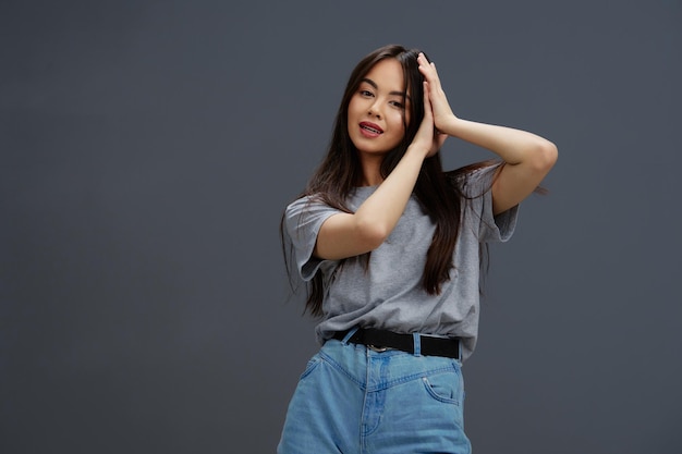 Jovem em uma camiseta e jeans posando estilo jovem fundo cinza