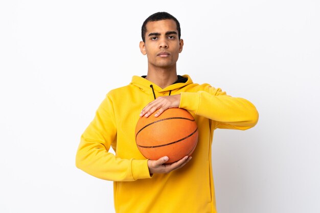 Jovem em uma parede branca isolada jogando basquete