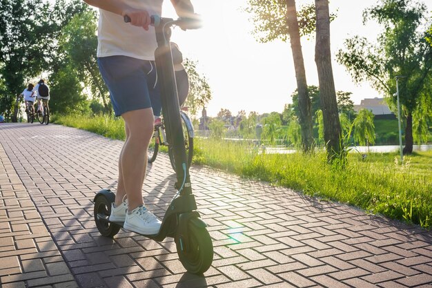 Jovem em uma scooter moderna no parque em um dia ensolarado de transporte ecológico