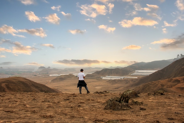 Jovem em viagem observando o horizonte e um céu impressionante