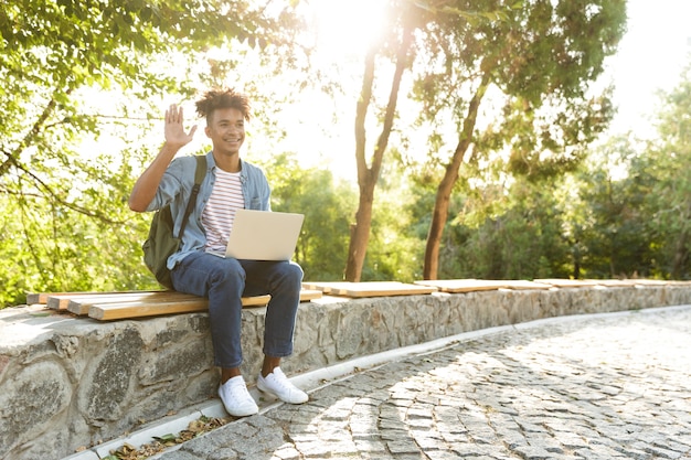 Jovem emocional em um parque ao ar livre usando um laptop