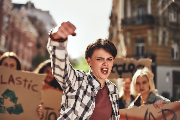 Jovem emocional gritando um slogan e liderando um grupo de manifestantes na estrada