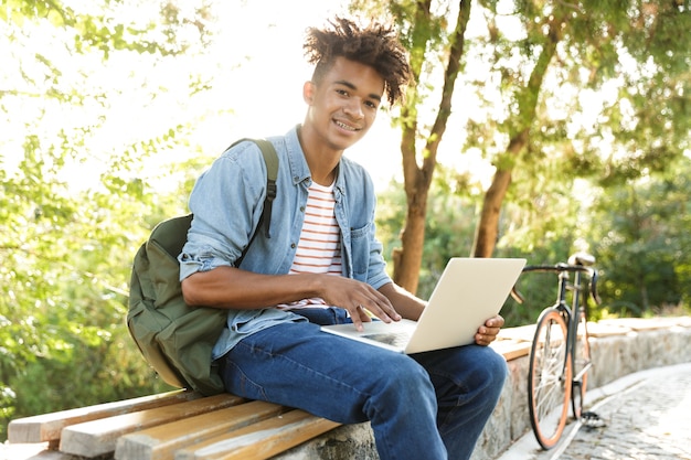 Foto jovem emocional no parque ao ar livre usando um laptop