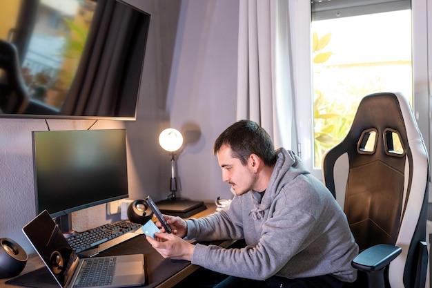 Foto jovem empreendedor comprando online pelo celular com o cartão na mão