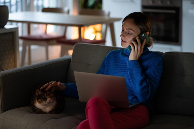 Jovem empresária acariciando cabeça de gato no sofá conversa com colega discutindo projeto de negócios