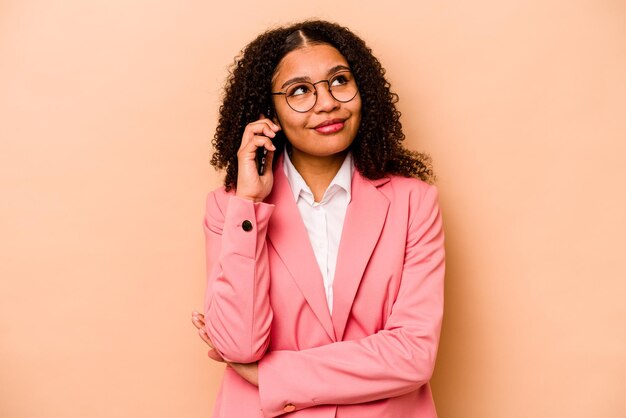 Jovem empresária afro-americana segurando telefone celular isolado em fundo bege