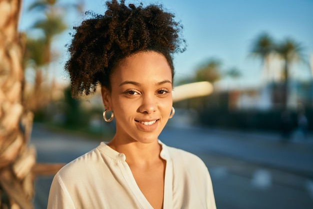 Jovem empresária afro-americana sorrindo feliz em pé na cidade