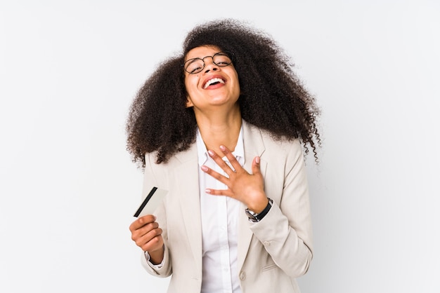 Jovem empresária afro segurando um cartão de crédito isolado Jovem empresária afro segurando um crédito carlaughs em voz alta mantendo a mão no peito.