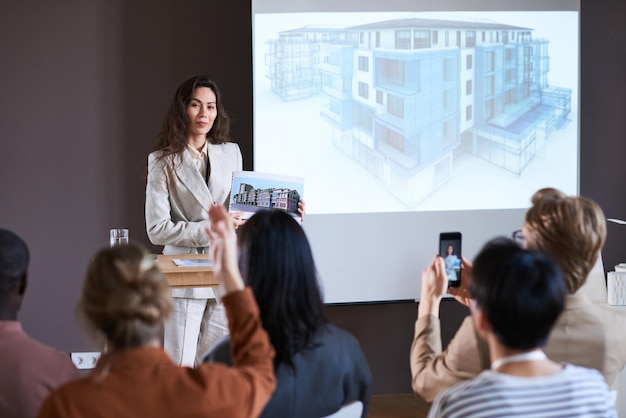 Jovem empresária apresentando o projeto de um novo edifício moderno para empresários na apresentação