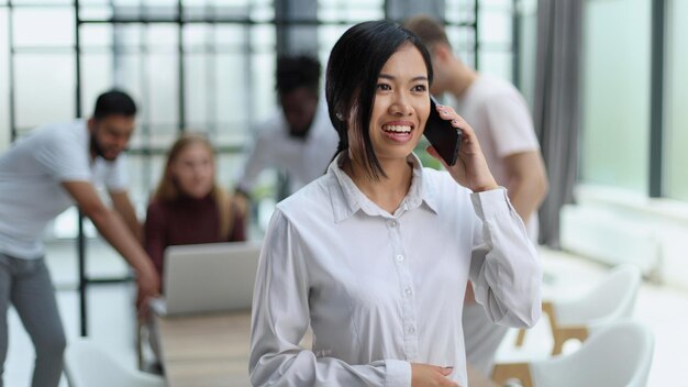 Jovem empresária asiática de camisa branca falando ao telefone