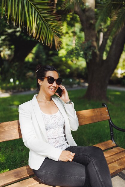 Jovem empresária asiática em blazer casual fazendo telefonema ao ar livre