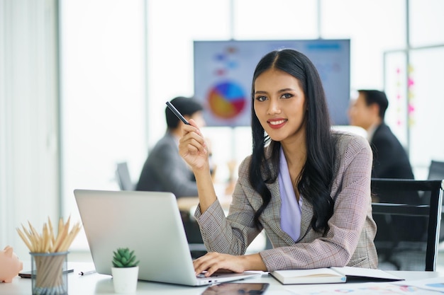 Foto jovem empresária asiática feliz trabalhando e usando um laptop de computador e pensando em ideias para seus negócios