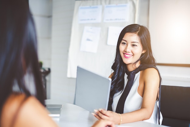 Jovem empresária asiática no escritório moderno discutindo com o colega e durante a reunião