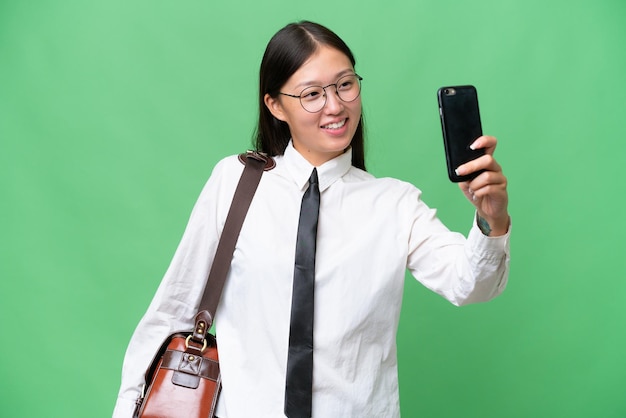 Jovem empresária asiática sobre fundo isolado fazendo uma selfie