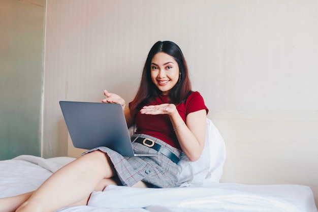 Jovem empresária asiática sorrindo enquanto trabalhava no laptop em casa Retrato de uma empresária positiva olhando para a tela do laptop dentro de casa