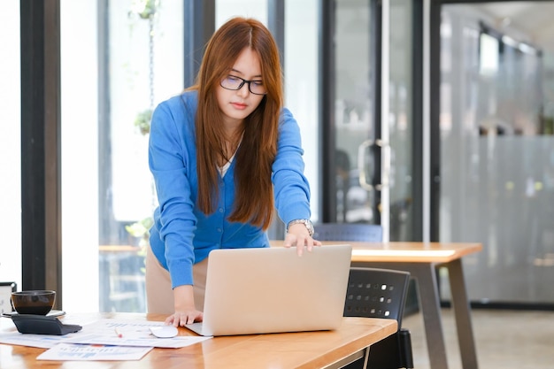 Foto jovem empresária asiática trabalhando no escritório usando laptop