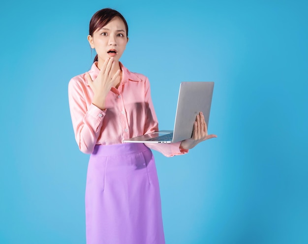 Jovem empresária asiática usando laptop em fundo azul