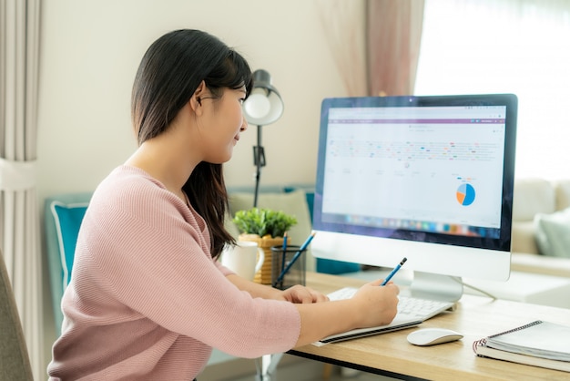 Jovem empresária asiática usando o trabalho do computador em casa