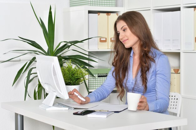 Jovem empresária atraente com laptop trabalhando no escritório