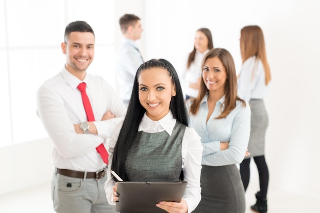 Jovem empresária bem sucedida orgulhosamente com sua equipe de negócios jovem e olhando para a câmera.