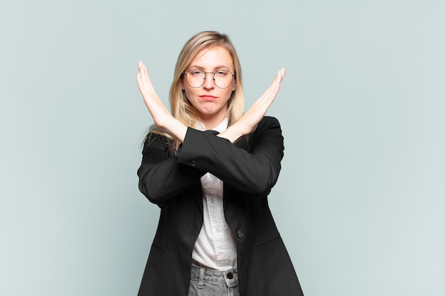 Jovem empresária bonita parecendo irritada e cansada de sua atitude, dizendo o suficiente! mãos cruzadas na frente, dizendo para você parar