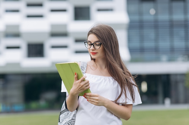 Jovem empresária bonita retrato usando dispositivo tablet em pé ao ar livre grande edifício urbano