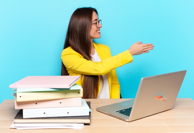 Jovem empresária bonita sorrindo, cumprimentando você e dando um aperto de mão para fechar um negócio de sucesso, o conceito de cooperação