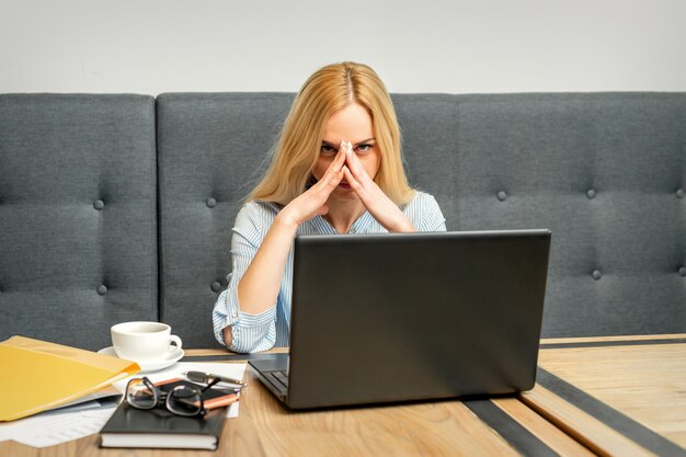 Jovem empresária caucasiana cansada do trabalho sentada à mesa de um café