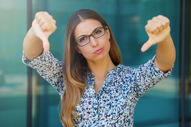 Foto jovem empresária chateada com polegares para baixo ao ar livre