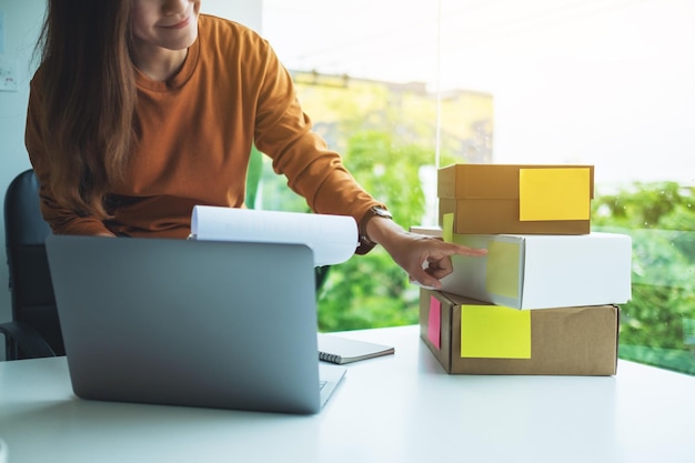 Foto jovem empresária checando pedidos de clientes para compras online e conceito de entrega