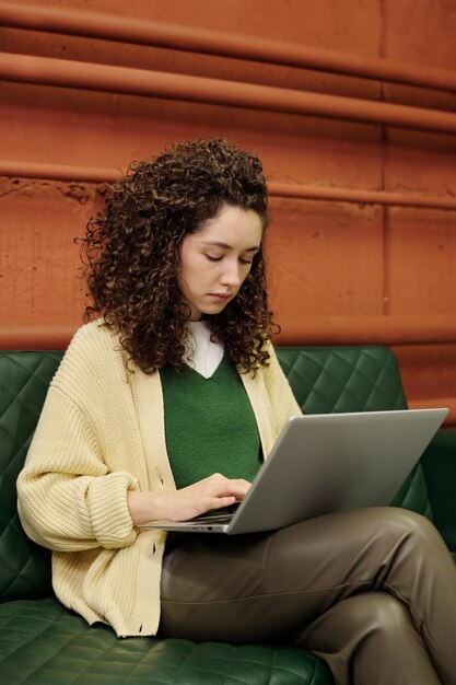 Foto jovem empresária com cabelo ondulado longo e grosso digitando no teclado do laptop