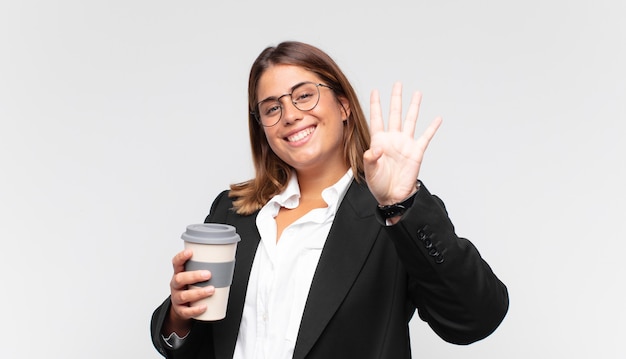 Jovem empresária com um café sorrindo e parecendo amigável, mostrando o número quatro ou o quarto com a mão para a frente, em contagem regressiva