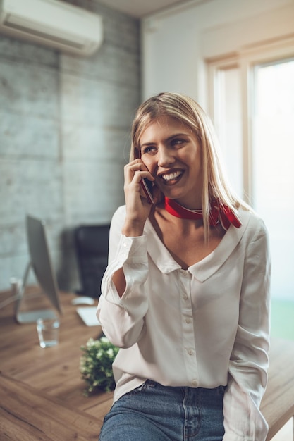 Jovem empresária de sucesso falando em um telefone inteligente no escritório.